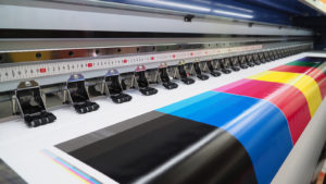 A test page with various bright colors is shown printing from a wide format inkjet printer.