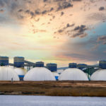 Several natural gas tanks with a sunrise in the background